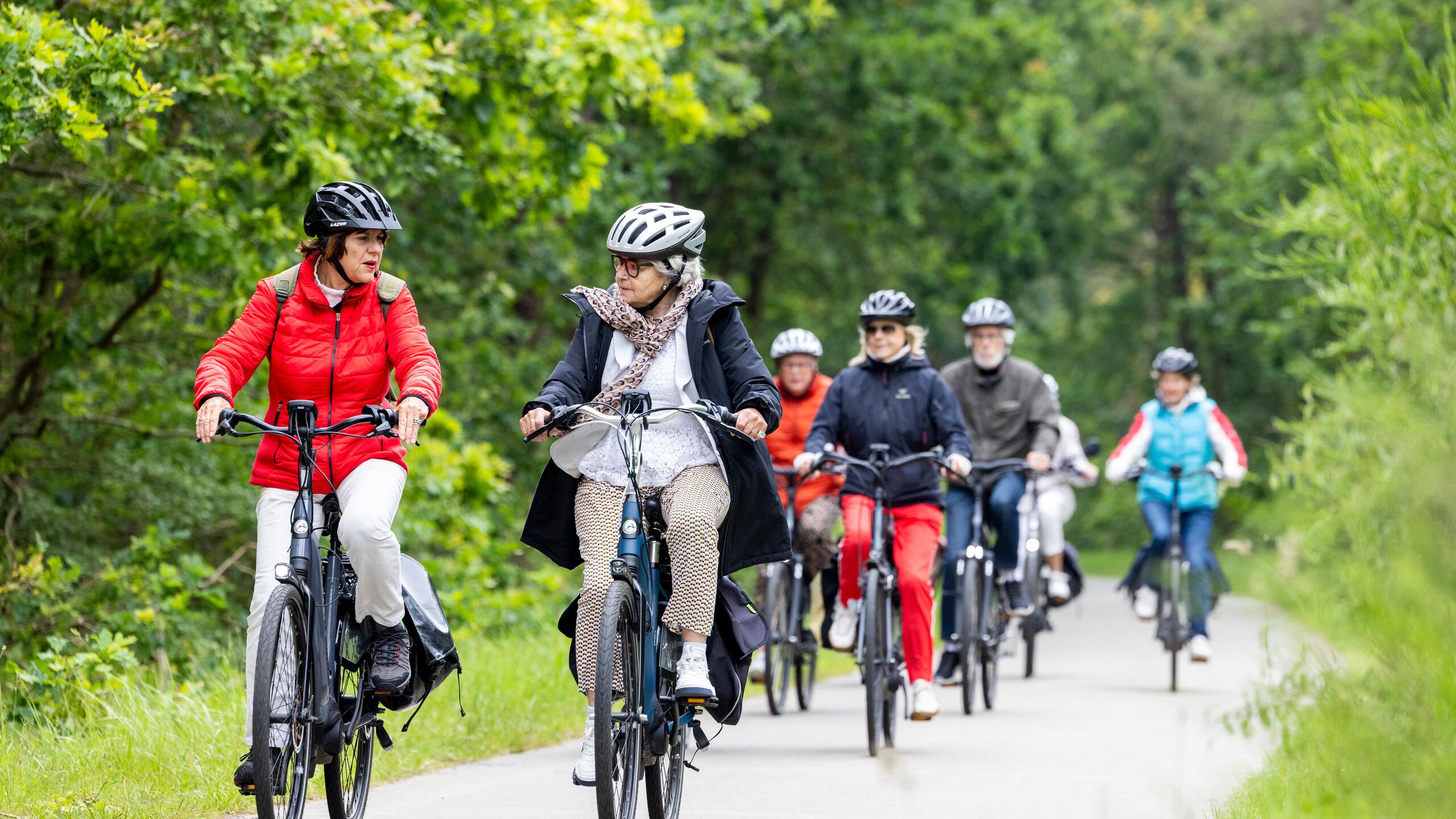 Senioren fietsen in groepsverband met fietshelm op