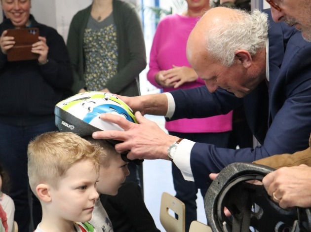 Wethouder plaatst helm op hoofd leerling