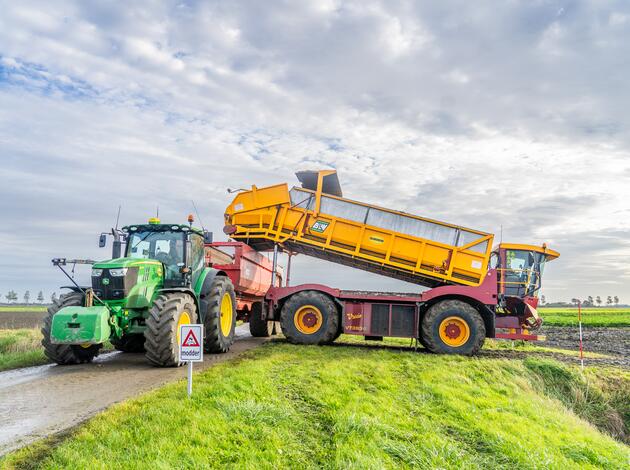 Trekker met kiepwagen rijdt het land af