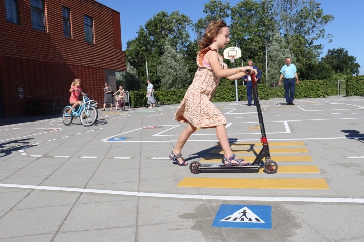 Meisje op stepje op verkeersplein