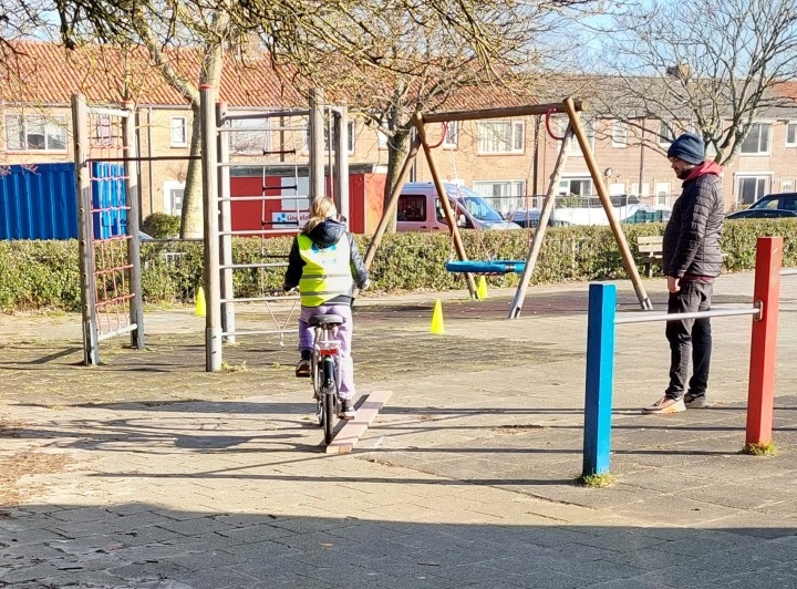 Leerling fietst over plank op schoolplein
