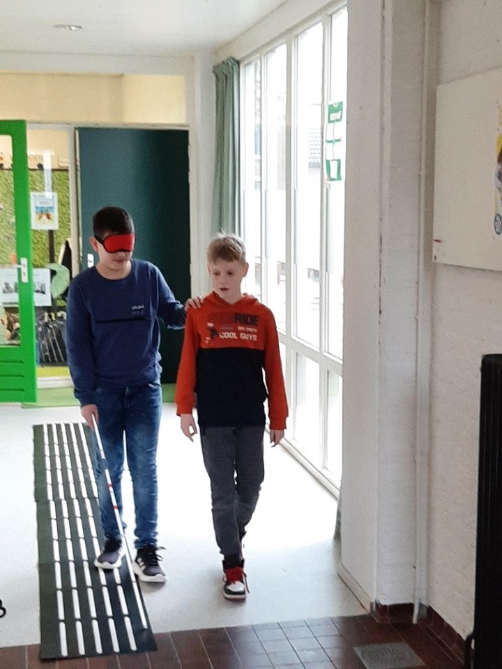 Leerlingen lopen met taststok in gang