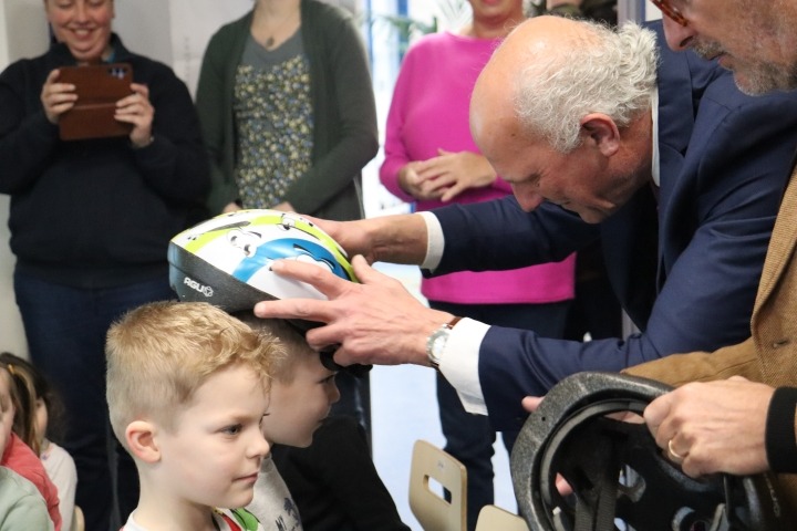 Wethouder plaatst helm op hoofd leerling
