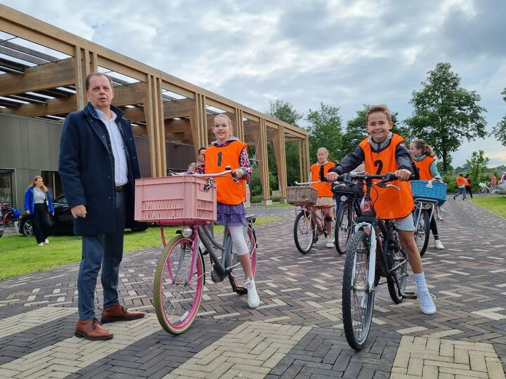 Wethouder en leerlingen op fiets tijdens verkeersexamen