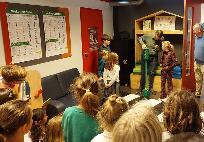 Kinderen kijken naar wethouder die werking stoplicht uitlegt