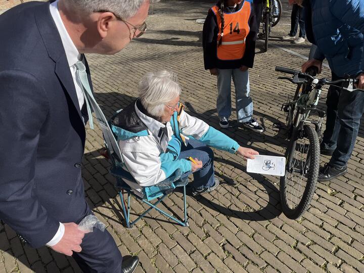 Gedeputeerde kijkt toe bij fietsenkeuring abdijplein door medewerker VVN
