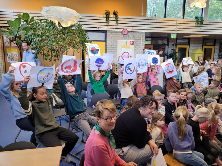 Leerlingen houden gemaakte tekeningen omhoog