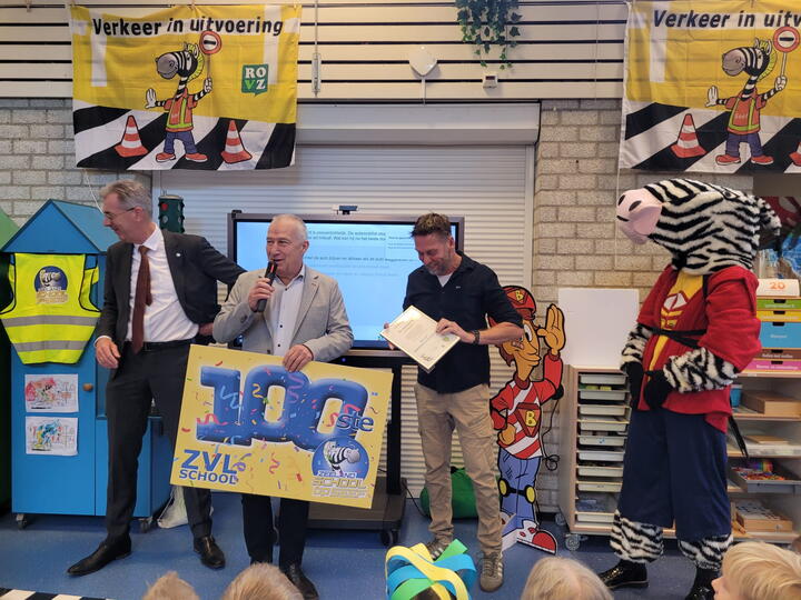 Gedeputeerde, wethouder houden bord omhoog met 100e ZVL school