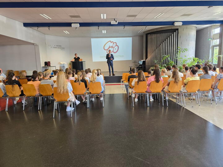 Gedeputeerde spreekt leerlingen toe in aula