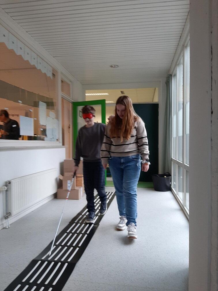 Leerlingen lopen met taststok in gang