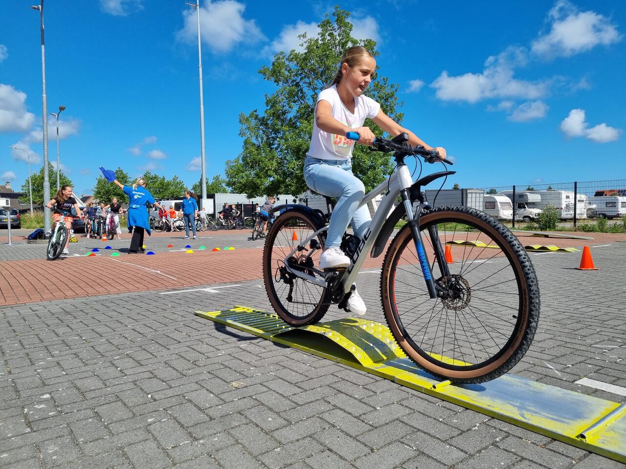Leerling rijdt op fiets over hindernis tijdens Fietsmasters