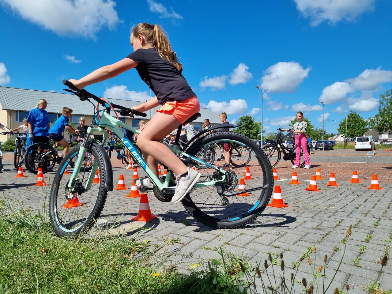 Leerling rijdt op fiets over hindernis tijdens Fietsmasters