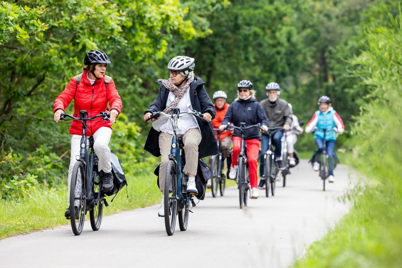 Senioren fietsen in groepsverband met fietshelm op