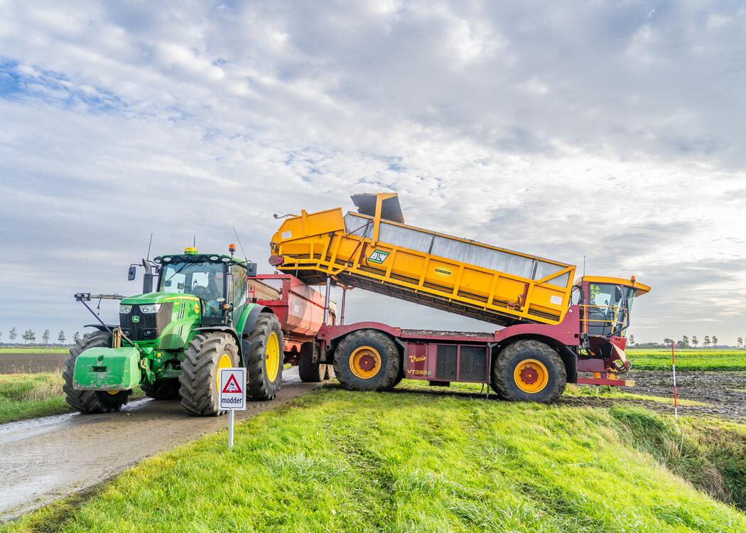 Trekker met kiepwagen rijdt het land af