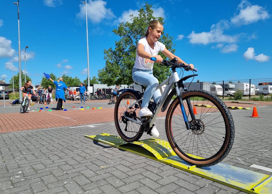 Leerling rijdt op fiets over hindernis tijdens Fietsmasters